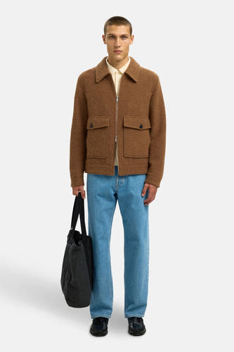 Bruine, korte jas van SELECTED, met opgestikte zakken, gecombineerd met een crèmekleurig shirt, blauwe jeans en een zwarte tote bag.