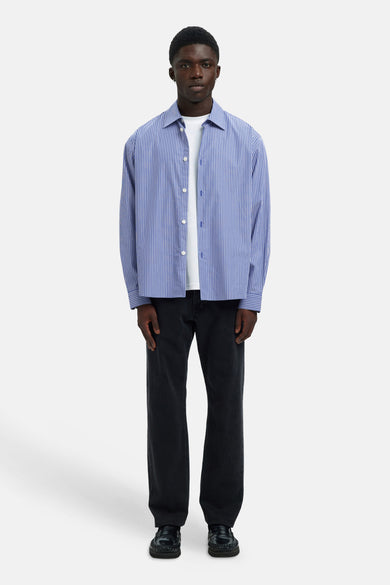 Blauw overhemd met lange mouwen van SELECTED, met verticale strepen, gedragen over een wit T-shirt met zwarte broek en schoenen.