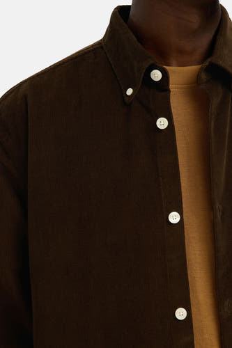Bruin corduroy overhemd met lange mouwen van SELECTED, met witte knopen en een bruin T-shirt eronder.