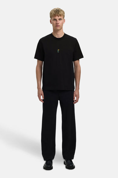Zwart T-shirt met korte mouwen van SELECTED, met kleine geborduurde afbeelding en gecombineerd met wijde zwarte broek en zwarte schoenen.
