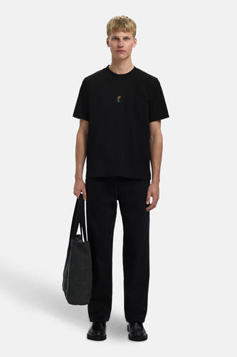 T-shirt noir à manches courtes de SELECTED, avec une petite impression sur la poitrine et porté avec un pantalon noir et un sac.