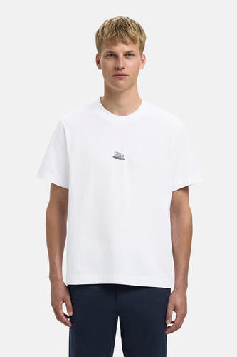 Wit T-shirt met korte mouwen van SELECTED, met kleine print op de borst, gedragen met donkerblauwe broek.
