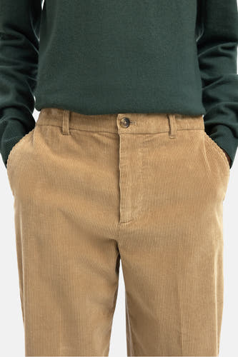 Bruine broek van SELECTED, corduroy textuur, met steekzakken en een groen gebreide trui.
