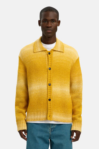 Veste jaune de SELECTED, portée avec un T-shirt blanc et des jeans bleus larges avec des loafers en cuir noir.