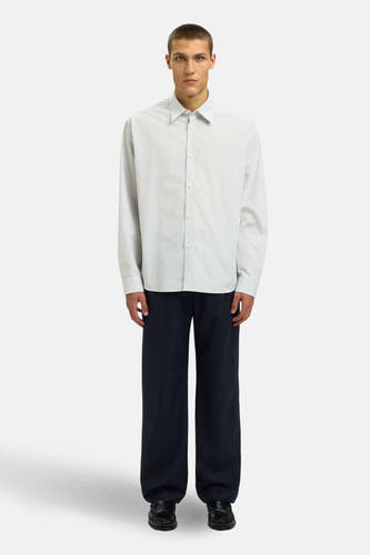 Wit overhemd met lange mouwen van SELECTED, gestreept met lichtblauwe lijnen, gecombineerd met een donkerblauwe pantalon en zwarte schoenen.