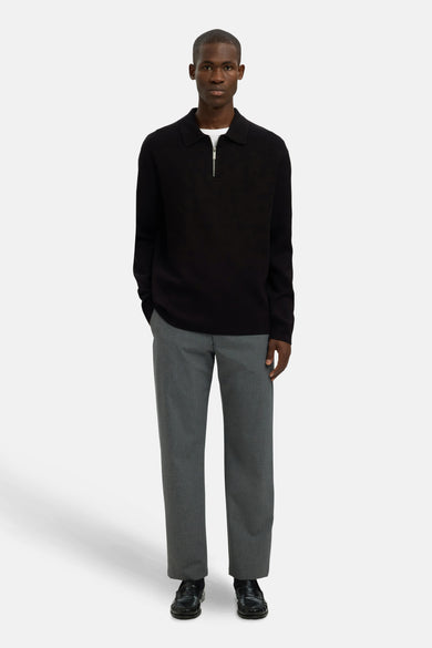 Zwarte trui met ronde hals van SELECTED, gedragen over een wit T-shirt en een grijze pantalon met zwarte schoenen.
