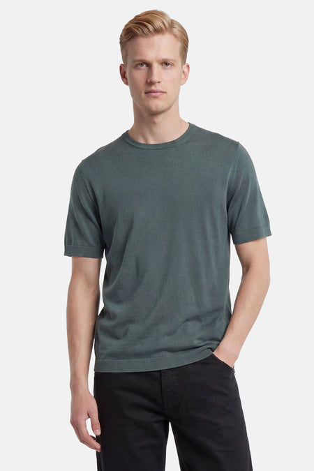 Groene pullover met ronde hals van SELECTED, met korte mouwen en fijne brei, gedragen door een man met zwarte broek.