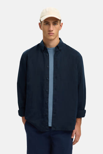 Blauw overhemd met lange mouwen van SELECTED, gedragen over een blauw T-shirt en gecombineerd met een beige pet.