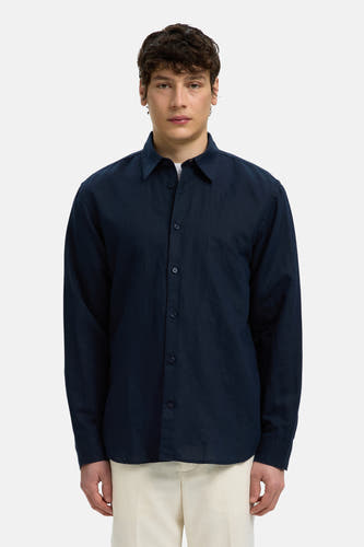 Blauw hemd met lange mouwen van SELECTED, met kraag en knopen, gedragen door een model over een wit T-shirt en een lichte broek.