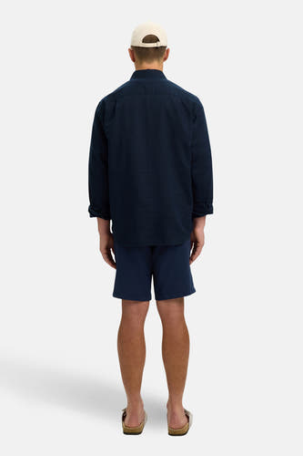 Blauw hemd met lange mouwen van SELECTED, met een losse pasvorm, gedragen met blauwe shorts en sandalen.