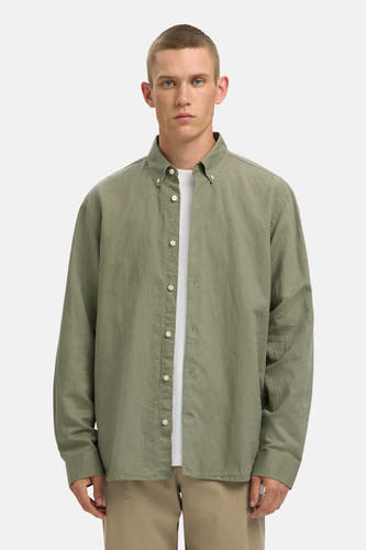 Groen overhemd met lange mouwen van SELECTED, gedragen over een wit T-shirt en kaki broek.
