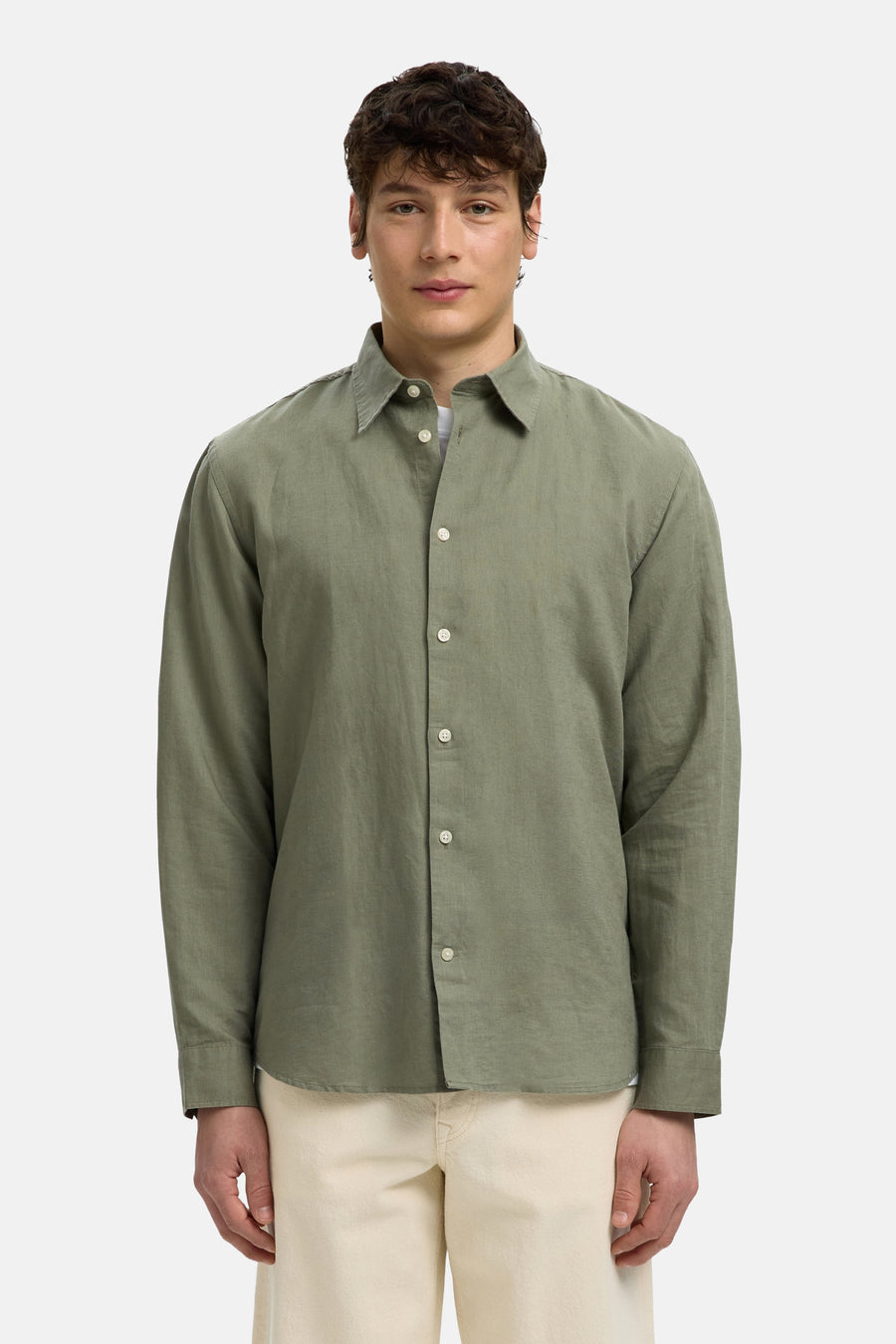 Groen hemd met lange mouwen van SELECTED met witte knopen en open kraag, gedragen op een lichte broek.
