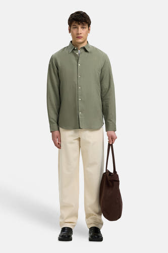 Groen hemd met lange mouwen van SELECTED, gecombineerd met crème broek, zwarte instappers en bruine tas.