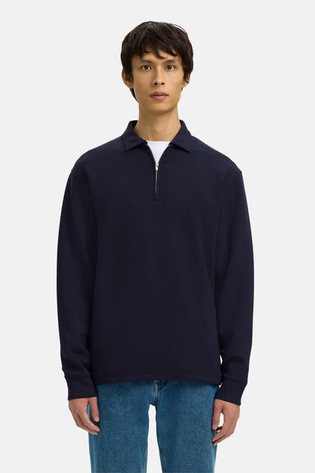 Pull bleu de SELECTED, porté avec un t-shirt blanc, un jean bleu et des chaussures noires.