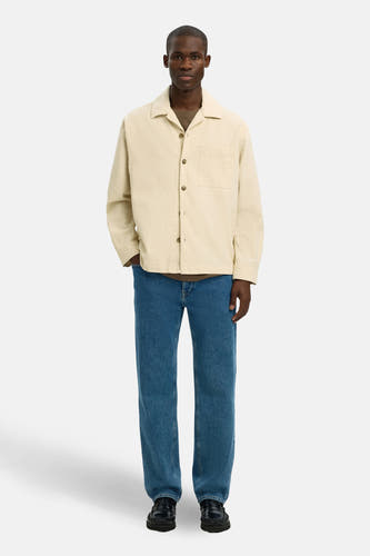 Ecru hemd van SELECTED, met lange mouwen, knoopsluiting en borstzak, gecombineerd met blauwe jeans en zwarte loafers.