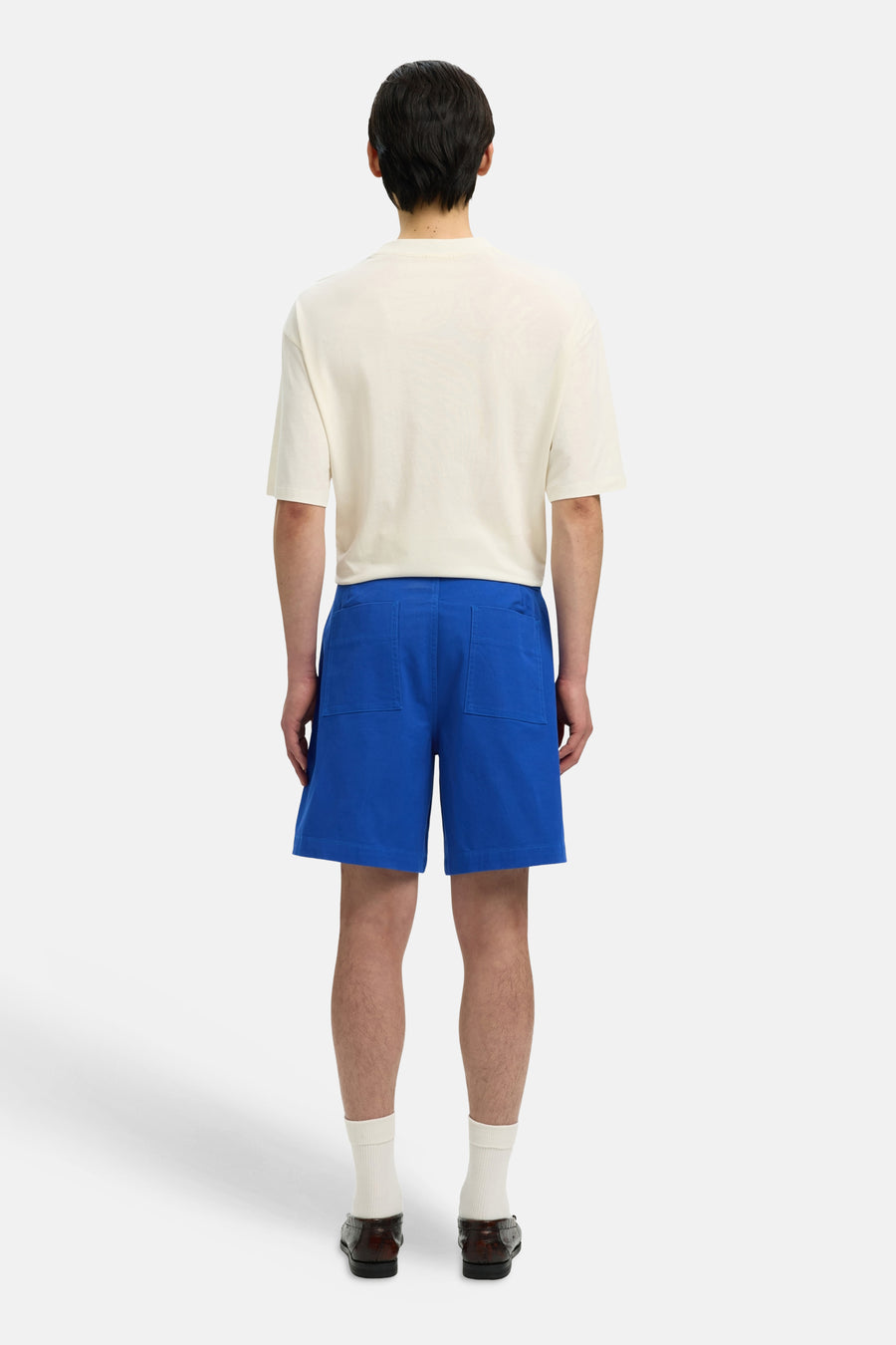 Short bleu de SELECTED, vu de dos, avec des chaussettes blanches et des mocassins marron.