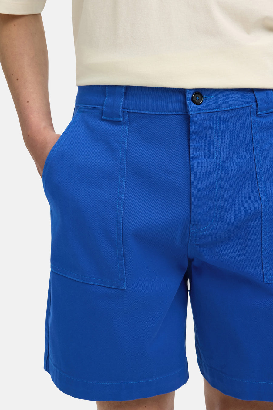 Short bleu de SELECTED, avec poches plaquées et fermeture à boutons, porté avec un t-shirt de couleur crème.