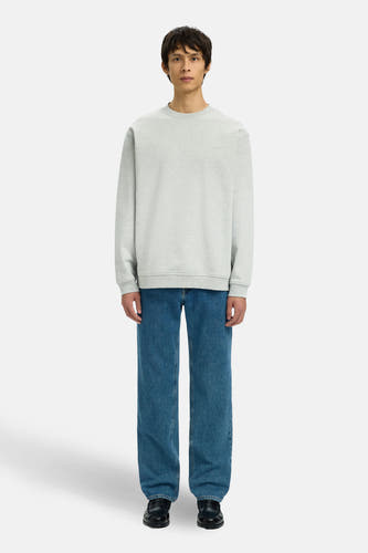 Grijze trui met ronde hals van SELECTED, gedragen met blauwe jeans en zwarte loafers.