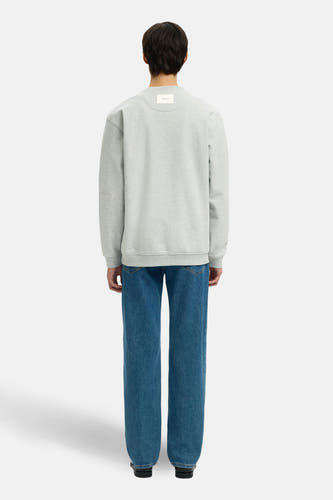 Grijze sweater van SELECTED, met lange mouwen, gecombineerd met blauwe jeans en zwarte schoenen, gezien van achteren.
