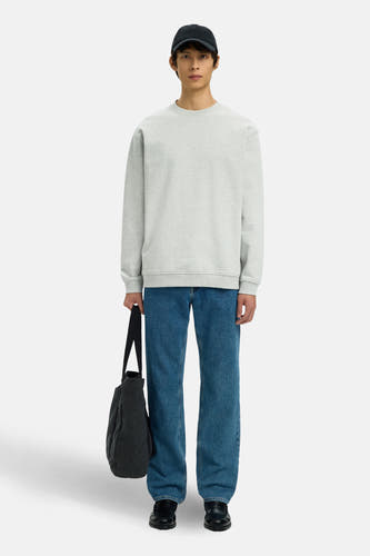 Grijze sweater van SELECTED, met lange mouwen, gedragen met blauwe jeans en zwarte pet.