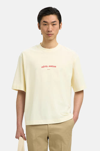 T-shirt écru de SELECTED, avec texte rouge "Hôtel Amour" et porté avec un pantalon kaki.
