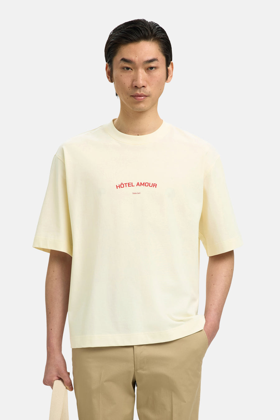 T-shirt écru de SELECTED, avec texte rouge "Hôtel Amour" et porté avec un pantalon kaki.
