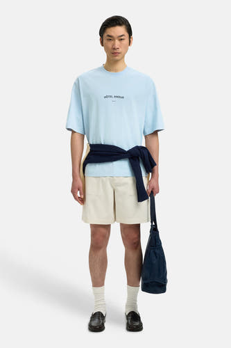 T-shirt bleu de SELECTED, à manches courtes, avec un pull noué et un sac à la main.