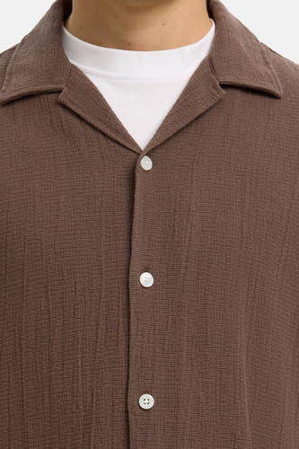 Bruin overhemd met korte mouwen van SELECTED, met resortkraag, gestructureerde stof en witte knopen over een wit T-shirt.