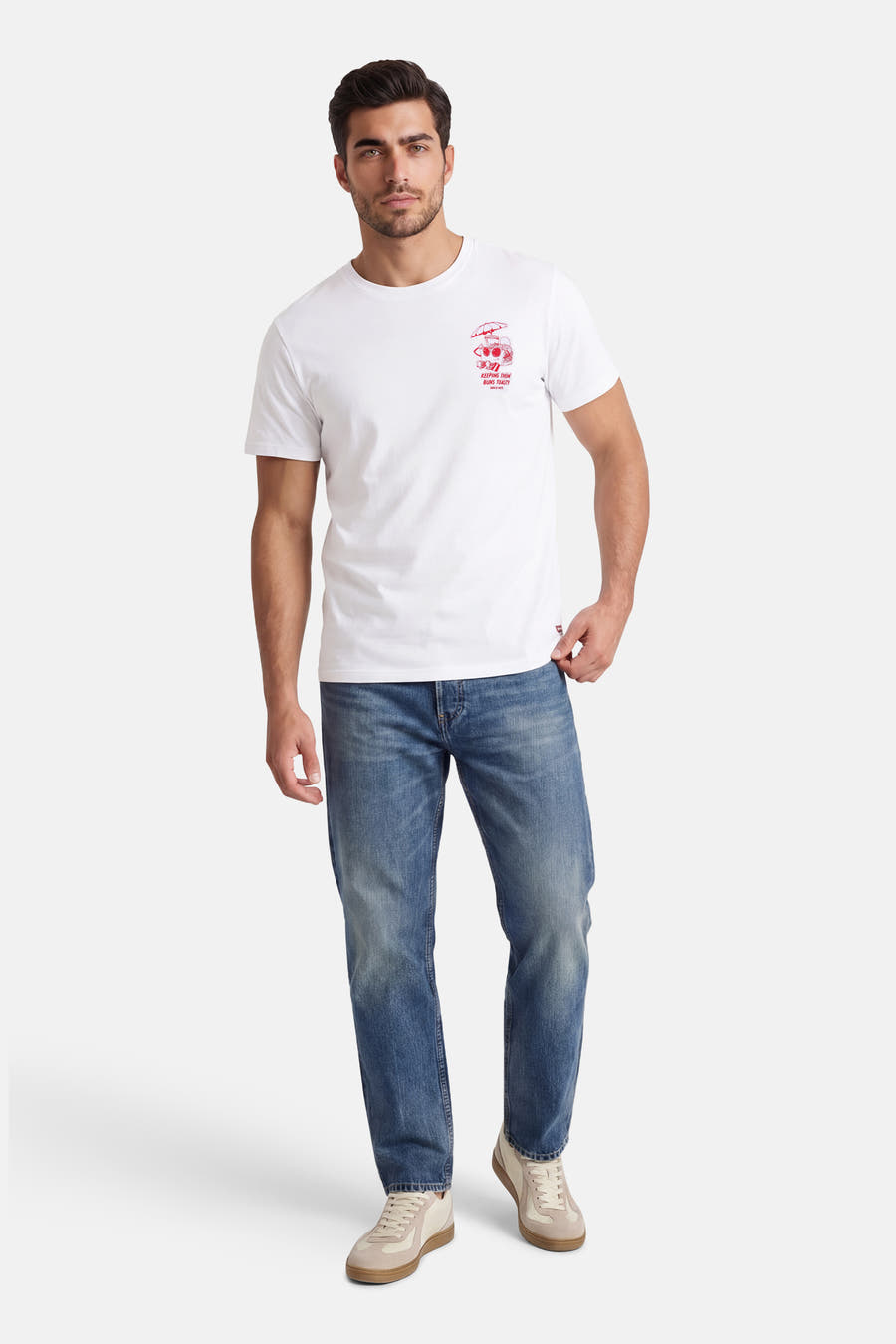 Wit T-shirt met korte mouwen van Levi's®, met een kleine rode print op de borst en gedragen met blauwe jeans en crèmekleurige sneakers.