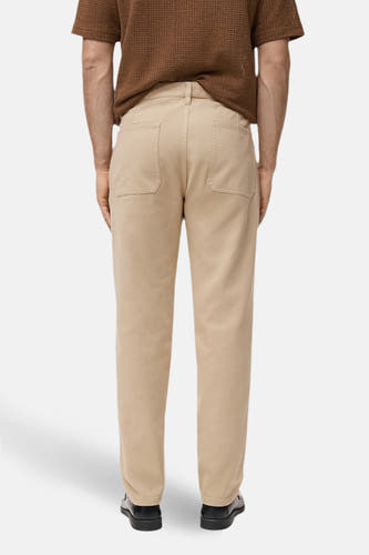 Beige kleurbroek van MANGO, gezien van achteren met achterzakken en zwarte schoenen.
