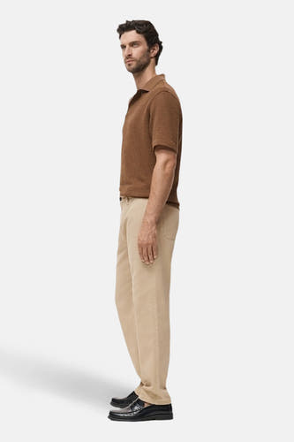 Beige colorbroek van MANGO, gezien van de zijkant, gecombineerd met een bruin poloshirt en zwarte schoenen.
