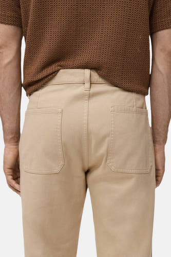 Beige kleurige broek van MANGO, met opgestikte zakken aan de achterkant, gezien van achteren.
