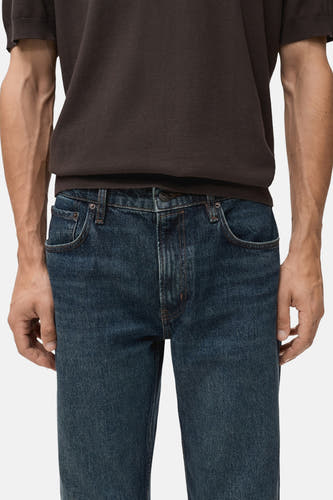 Slim fit jeans van donkerblauw denim van MANGO, close-up vooraanzicht met een bruin t-shirt.