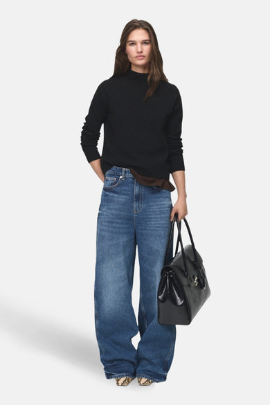 Zwarte trui met ronde hals van MANGO, gedragen met wijde jeans en een zwarte tas.