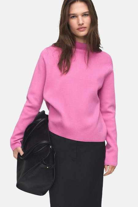 T-shirt rose avec col rond de MANGO, associé à une jupe noire longue et un sac main noir.