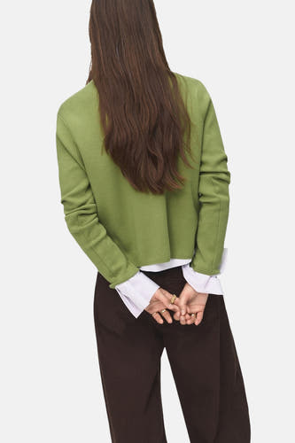 T-shirt vert avec col rond de MANGO, porté sur une chemise blanche et un pantalon marron, dos.
