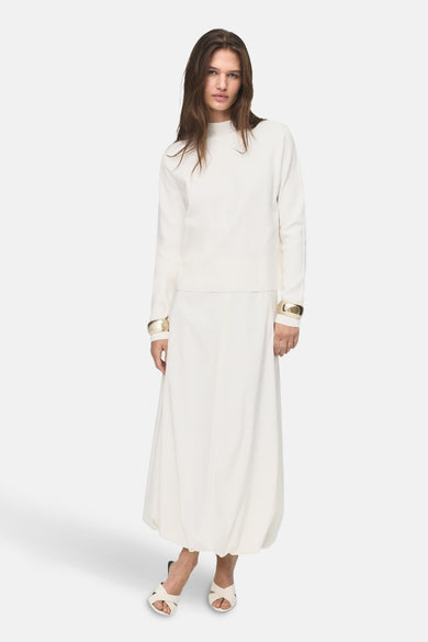 Witte trui met ronde hals van MANGO, met gouden armbanden en een lange, uitlopende rok.
