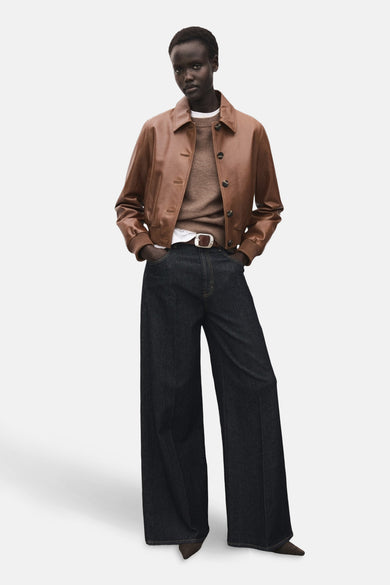Bruine trui met ronde hals van MANGO, gedragen onder een leren jas en wijde jeans met een bruine riem.