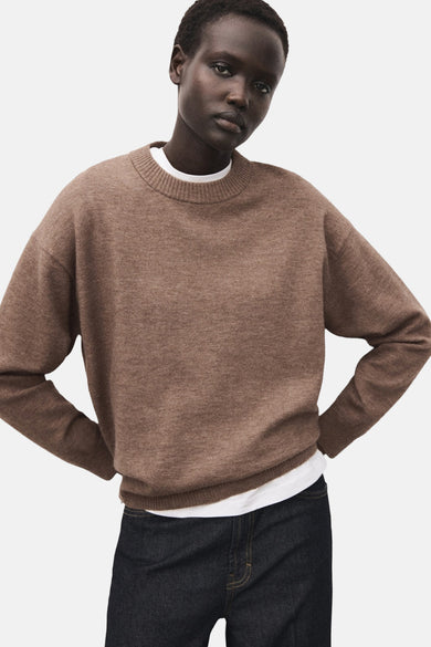 Bruine trui met ronde hals van MANGO, gedragen over een wit shirt en gecombineerd met een donkere jeans.