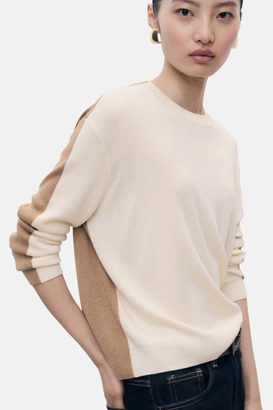 Pull beige à col rond de MANGO, avec des poches sur les manches et un short en jeans.