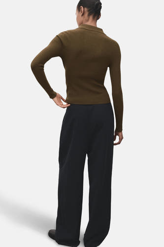 Khaki trui met ronde hals van MANGO, getextureerd, gecombineerd met een wijde zwarte broek.