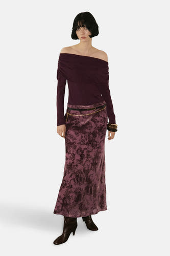 Bordeaux trui met ronde hals van MANGO, gedragen off-shoulder met een lange rok met paars bloemenpatroon en zwarte laarzen.