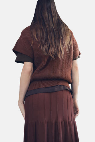 Bruine debardeur van MANGO, met ribstructuur, gecombineerd met een bruine rok met verticale plooien, gezien van achteren.
