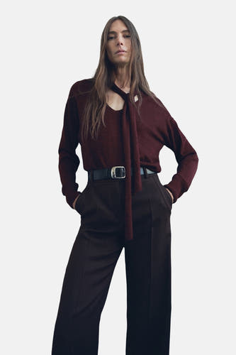 Bordeaux trui met ronde hals van MANGO, gestyled met een losse sjaal en donkere, hooggetailleerde pantalon met riem.
