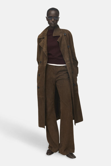 Bordeaux trui met ronde hals van MANGO, gedragen onder een bruine trenchcoat en broek.