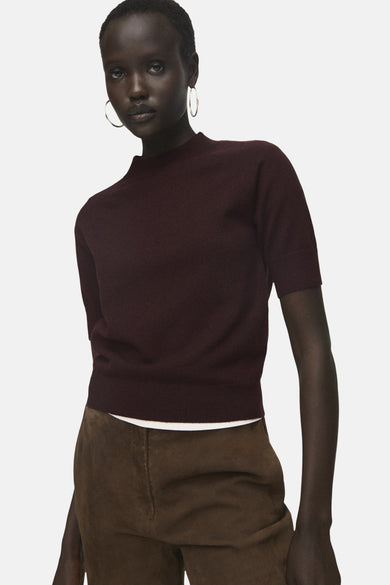 Bordeaux trui met ronde hals van MANGO, gedragen met bruine broek en zilveren oorringen.