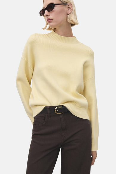 Gele trui met ronde hals van MANGO, gedragen met een riem en bruine broek.