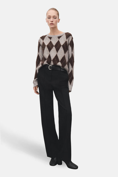 Multikleurige trui met ronde hals van MANGO, met ruitpatroon en gecombineerd met zwarte pantalon met riem.
