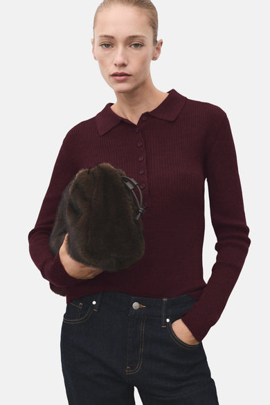 Bordeaux trui met ronde hals van MANGO, met een ribgebreide textuur, gedragen met een jeans en een tas van imitatiebont.
