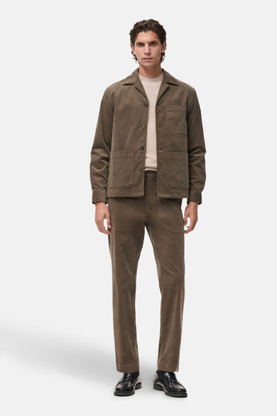 Pantalon marron de MANGO, avec une texture en laine côtelée et porté avec un chemisier beige et des chaussures noires.